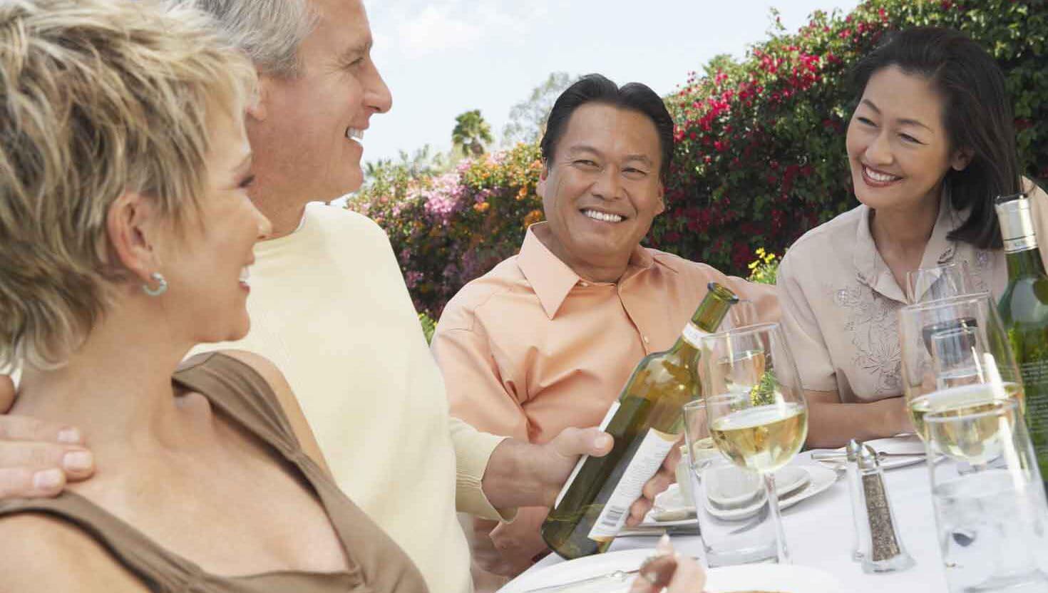 A group of persons smiling while drinking wine on a sunny day